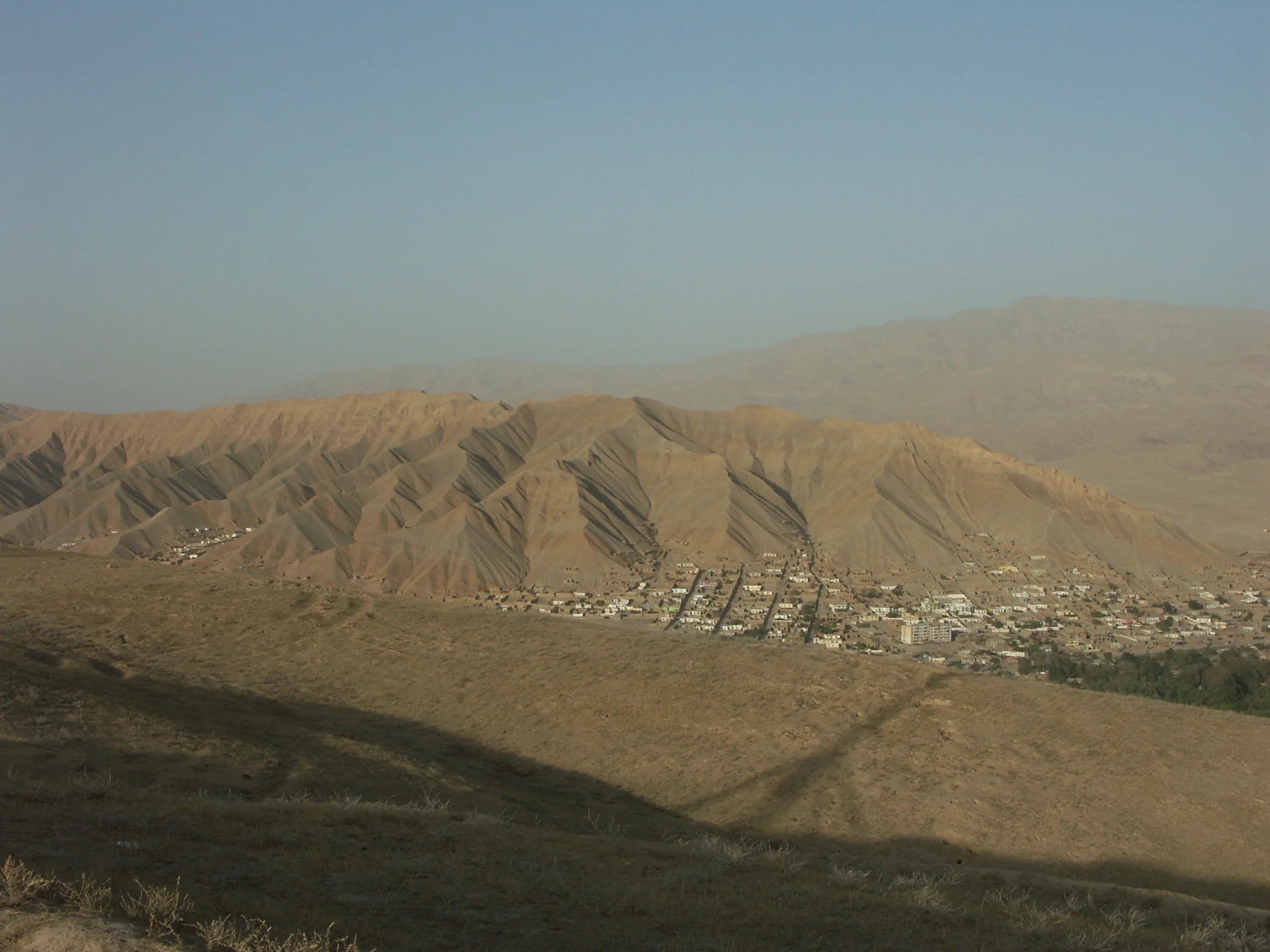 Buildings below steep, ridged hills in the valley of Pul-e Khumri, Baghlan Province.